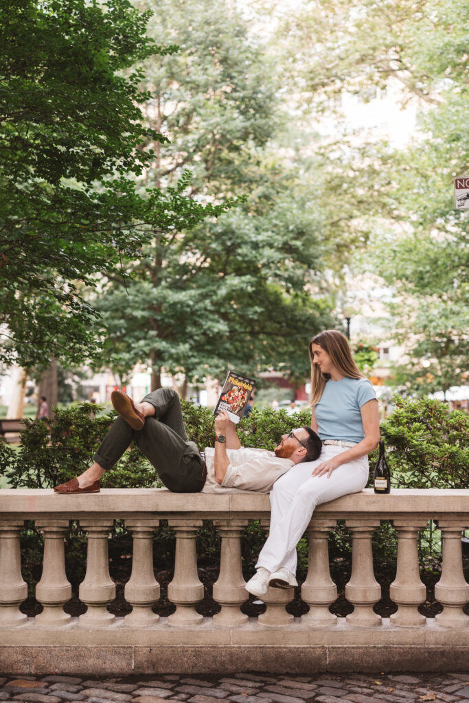 A couple sit together, read magazines and sip champagne in Rittenhouse Square. Taken by Philly wedding photographer Madison Neumann Photography. 