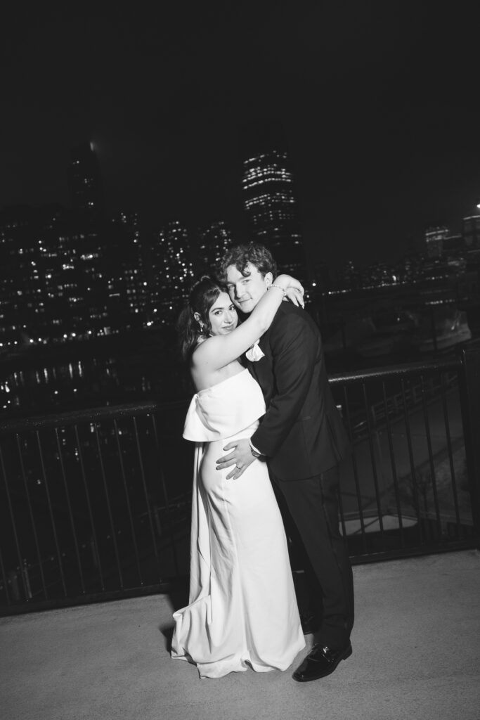 Bride and groom at night outside of their venue with cityscape in the background. Wedding day at Maritime Parc in Jersey City, NJ. Photographed by South Jersey, Philadelphia based wedding photographer Madison Neumann Photography.
