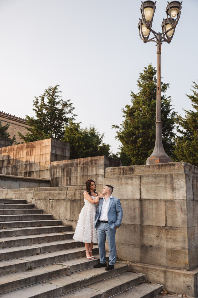 An engagement couple poses together on the Philadelphia Museum of Art Steps. Taken by Wedding Photographer Madison Neumann Photography. 