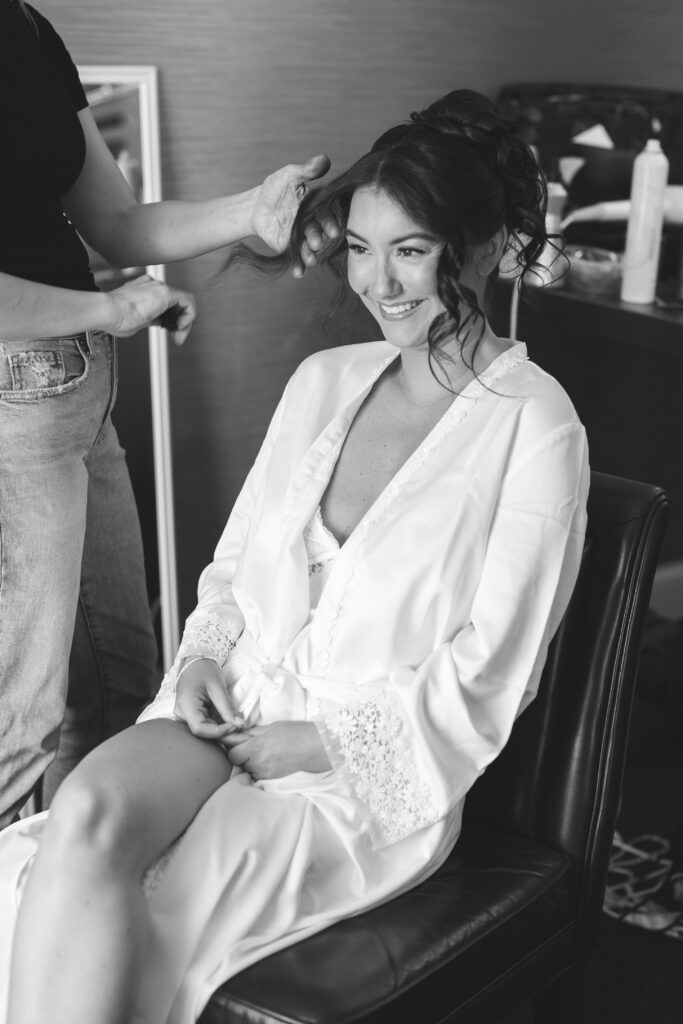 Bride gets her hair done as she gets ready for her wedding day, wearing a veil and gown. Wedding day at Downingtown Country Club in Downingtown, PA. Photographed by South Jersey, Philadelphia based wedding photographer Madison Neumann Photography.