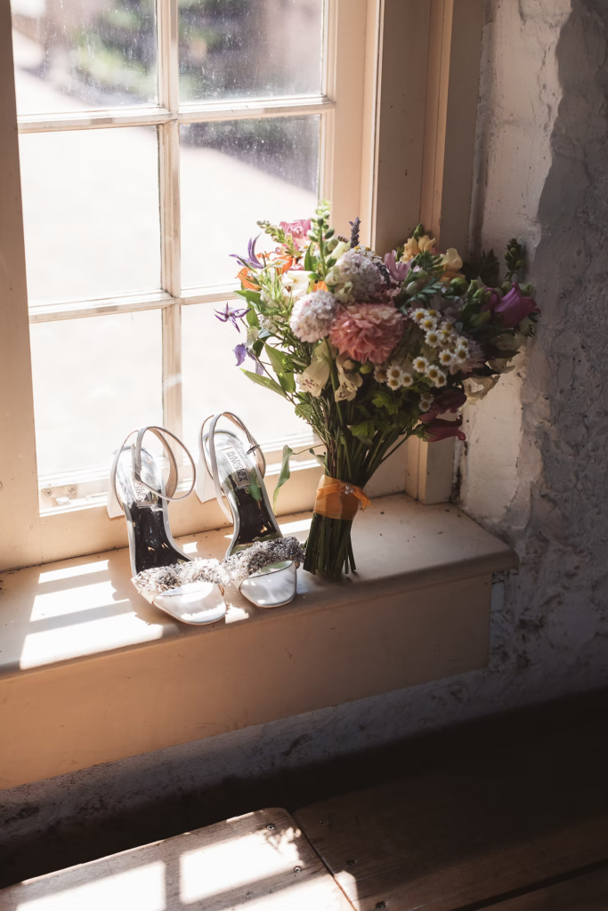 Bridal shoes and colorful bouquet on windowsill for wedding at Bartram's Garden in Philadelphia, PA. Photographed by South Jersey Philly wedding photographer Madison Neumann Photography.