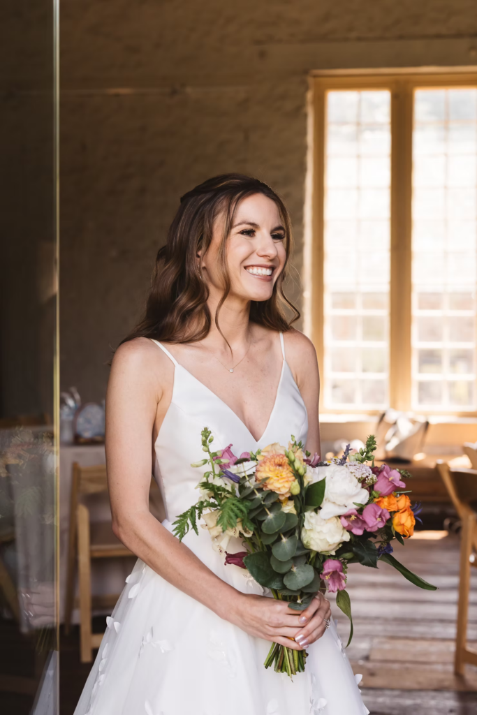 Bride smiles in gown holding bouquet getting ready for wedding at Bartram's Garden in Philadelphia, PA. Photographed by South Jersey Philadelphia wedding photographer Madison Neumann Photography.