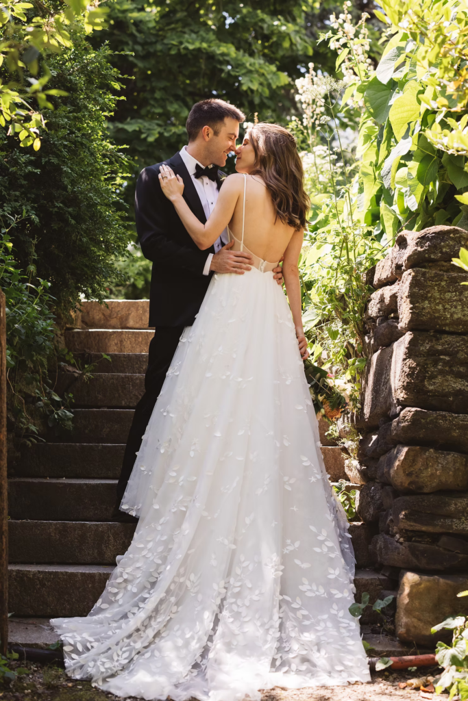Bride and groom embrace on steps of park for outdoor wedding at Bartram's Garden in Philadelphia, PA. Photographed by South Jersey Philly wedding photographer Madison Neumann Photography.