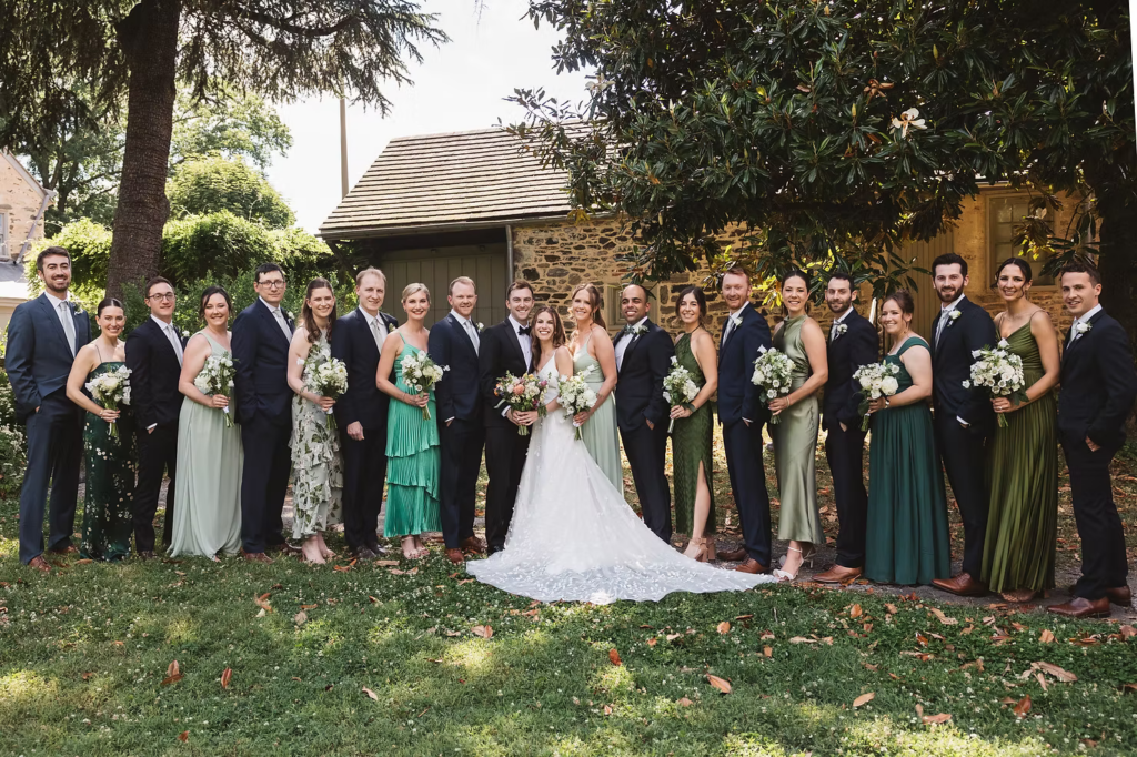 Bride and groom with wedding party, green tone bridesmaids dresses, for wedding at Bartram's Garden in Philadelphia, PA. Photographed by South Jersey Philly wedding photographer Madison Neumann Photography.