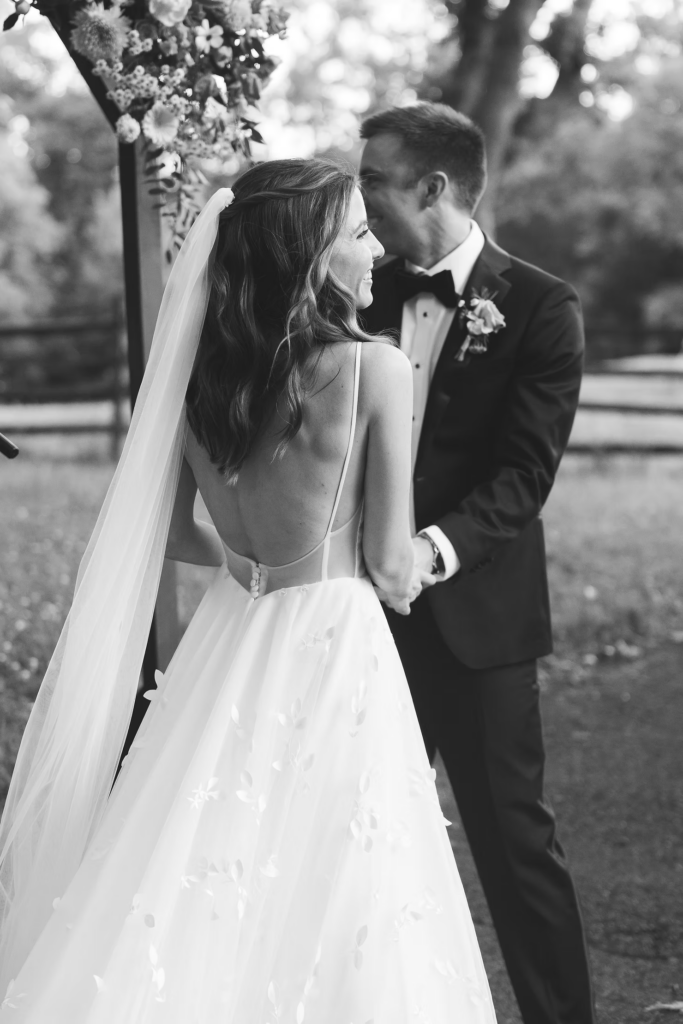 Black and white photo of bride and groom at the altar, arbor with florals, for outdoor wedding at Bartram's Garden in Philadelphia, PA. Photographed by South Jersey Philly wedding photographer Madison Neumann Photography.