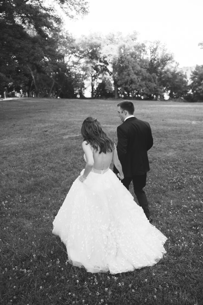 Bride and groom hold hands and run through field for black and white photo, for wedding at Bartram's Garden in Philadelphia, PA. Photographed by South Jersey Philly wedding photographer Madison Neumann Photography.