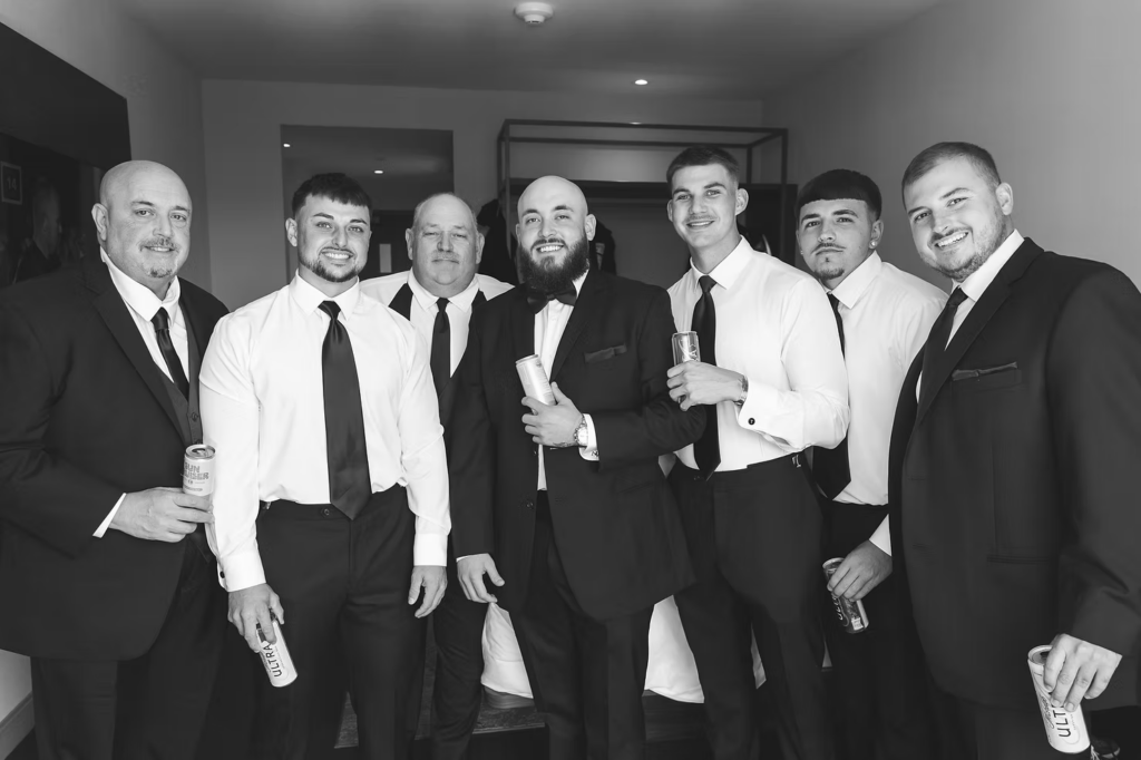 Black and white portrait of groom with groomsmen in tuxes and suits getting ready for wedding day at The Ivy at Ellis Preserve in Newtown Square, PA. Photographed by New Jersey, Pennsylvania region wedding photographer Madison Neumann Photography.
