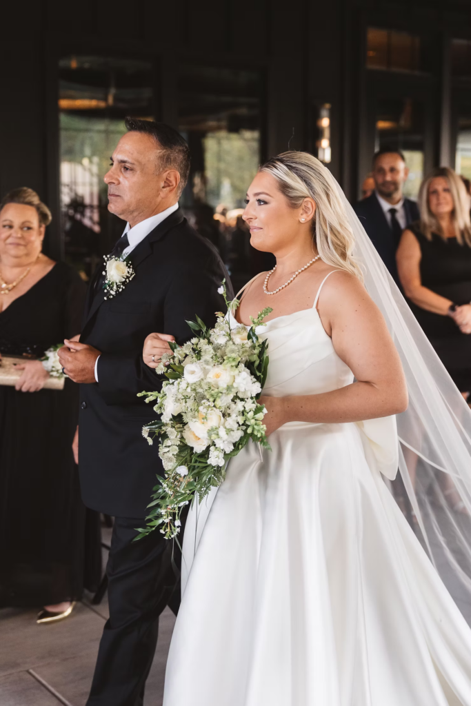 Bride emotional walking down the aisle to groom during wedding ceremony at The Ivy at Ellis Preserve by Finley Catering in Newtown Square, Pennsylvania. Photographed by NJ/PA region wedding photographer Madison Neumann Photography.