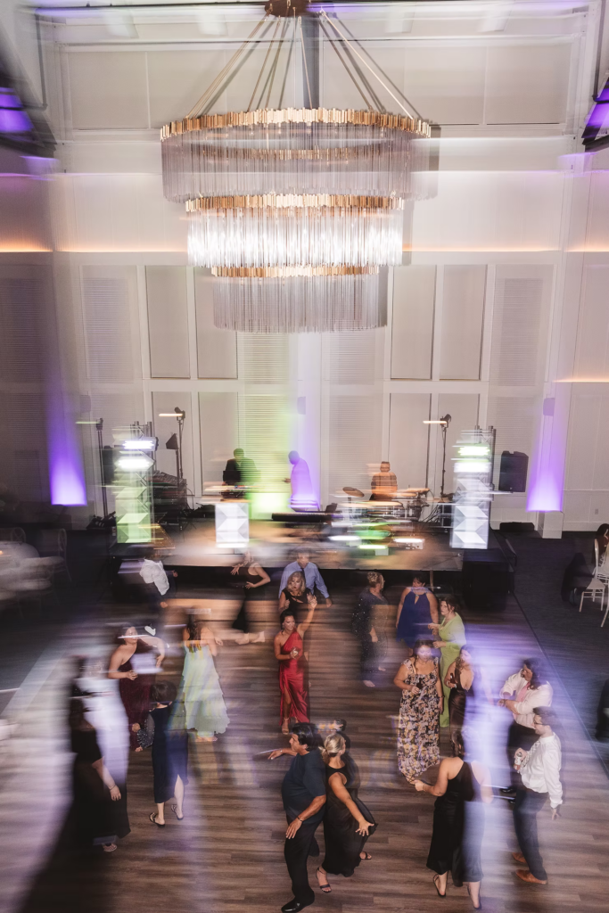 Shutter drag photograph of large chandelier accent and guests on the dance floor on wedding night at The Ivy at Ellis Preserve by Finley Catering in Newtown Square, Pennsylvania. Photographed by NJ, PA region wedding photographer Madison Neumann Photography.