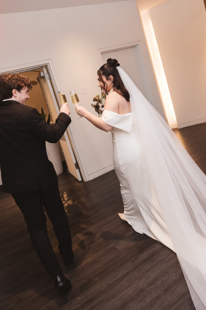 Newlywed bride and groom cheers with their champagne glasses after ceremony. Wedding day at Maritime Parc in Jersey City, NJ. Photographed by South Jersey, Philadelphia based wedding photographer Madison Neumann Photography.