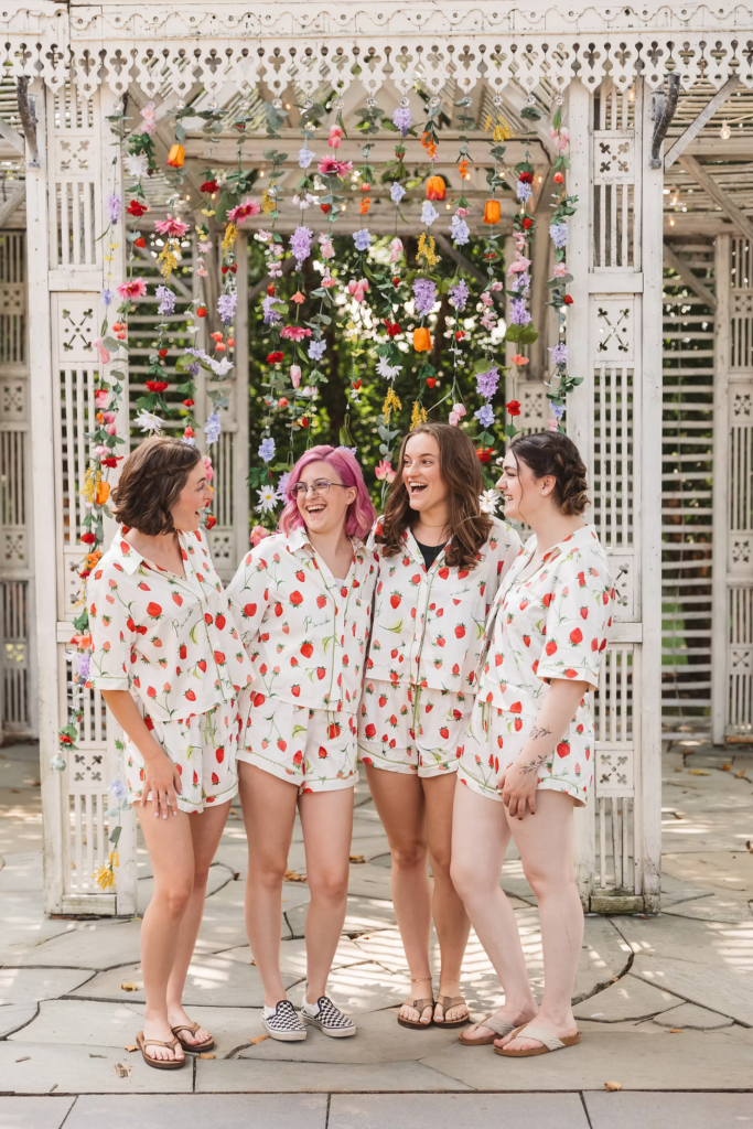Bride gets ready with her bridesmaids in matching strawberry pahjamas for her summer garden wedding at terrain in glen mills, PA. photo by Madison Neumann photography.