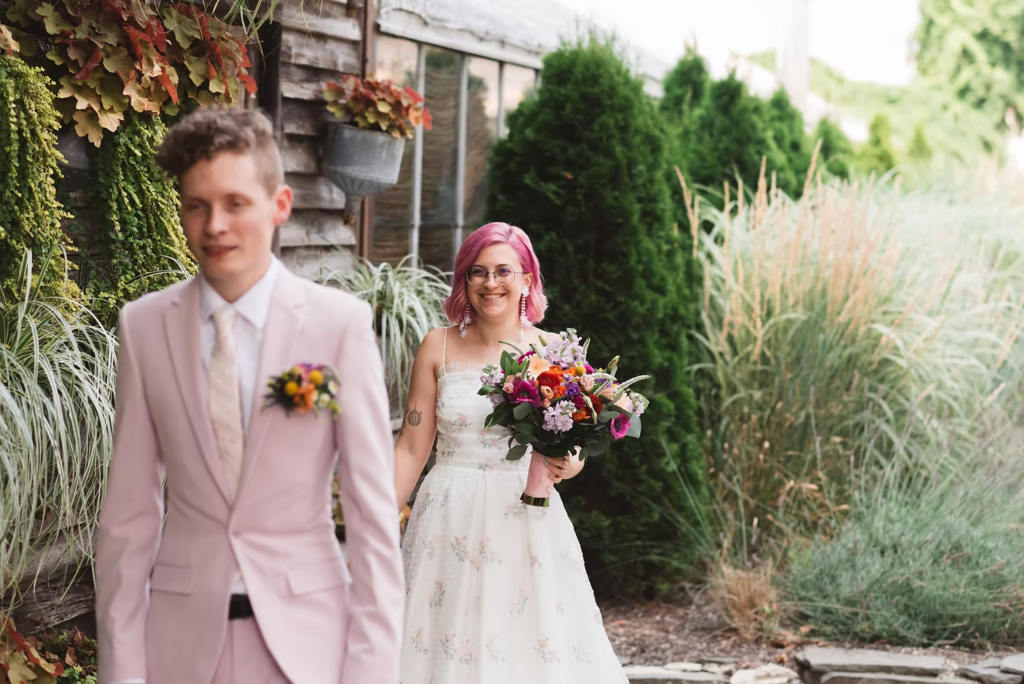 Bride and groom portrait at their first look at at their colorful garden party wedding at terrain in glen mills, PA. their first look is happening in front of a plant wall on the property, wooden and covered in green plants. Taken by philly wedding photographer Madison Neumann Photography.