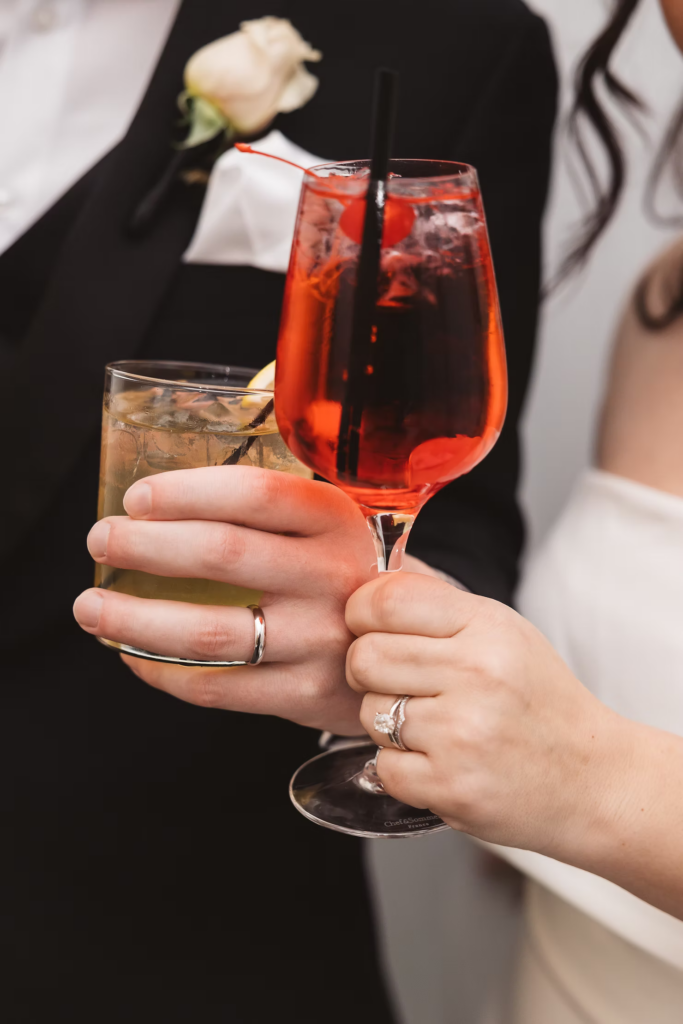 Bride and groom cheers with their cocktails in hand and wedding rings on their fingers. Wedding day at Maritime Parc in Jersey City, NJ. Photographed by South Jersey, Philadelphia based wedding photographer Madison Neumann Photography.