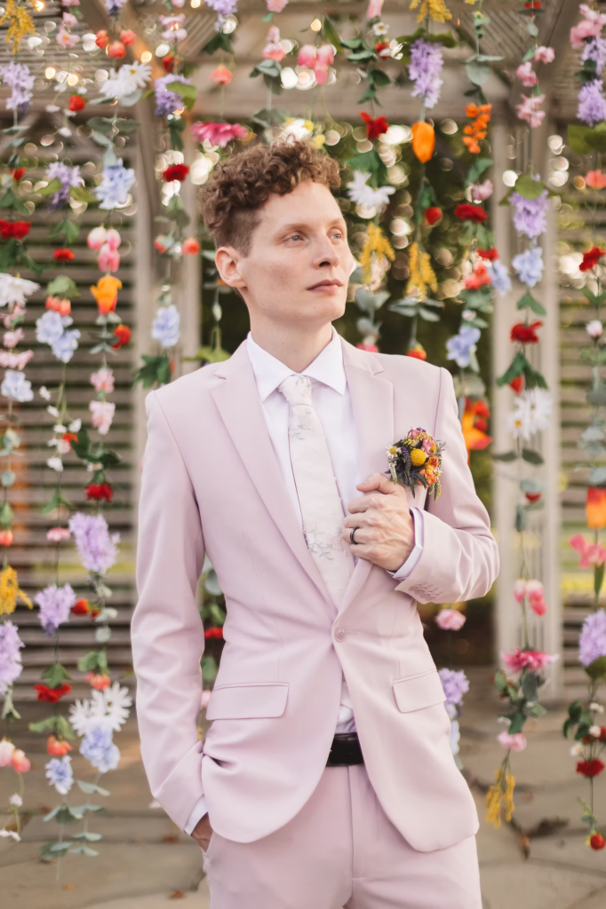 Groom poses in front of handmade backdrop at Terrain Glen Mills.