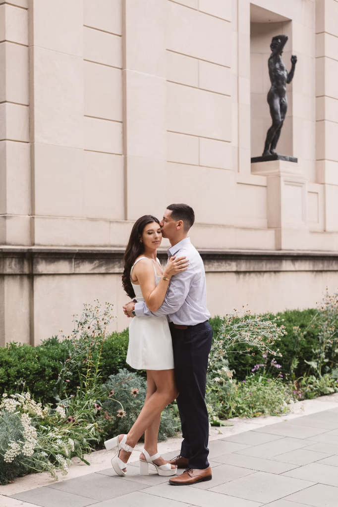 Fiancées pose together by plants and statue in the garden of The Rodin Museum in Philadelphia, PA. Photographed by Philly, South Jersey photographer Madison Neumann Photography.