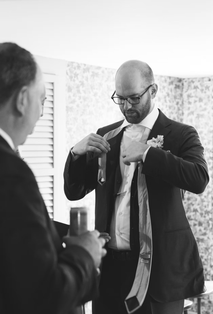 Groom putting on tie and getting ready for ceremony for Pennsylvania wedding in the Pocono Mountains. Photographed by South Jersey Philly Wedding Photographer Madison Neumann Photography.