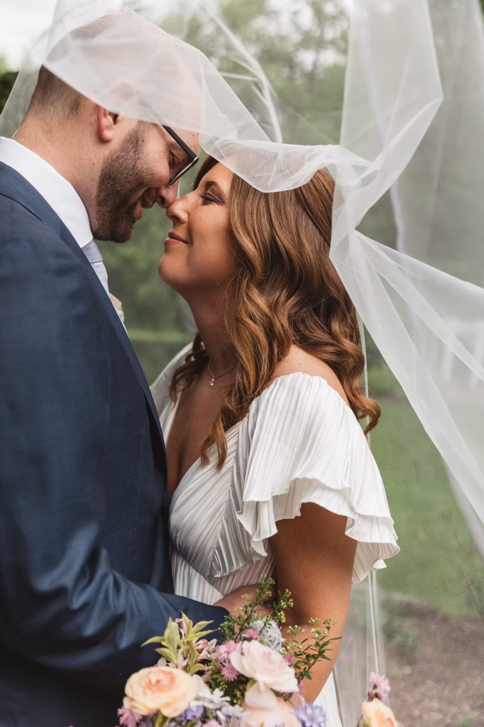 Bride and groom pose with greenery and bouquet for Pennsylvania wedding in the Pocono Mountains at The Lodge at Mountain Springs Lake. Photographed by South Jersey Philly Wedding Photographer Madison Neumann Photography.