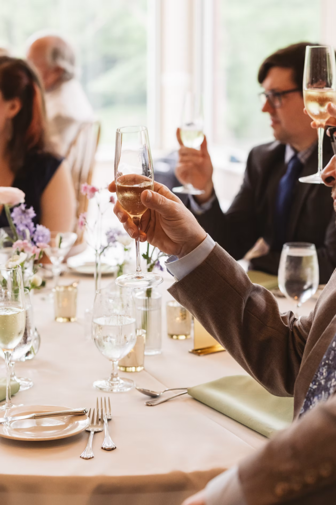 Wedding guests raise their champagne glasses for a toast for Pennsylvania wedding in the Pocono Mountains. Photographed by South Jersey Philly Wedding Photographer Madison Neumann Photography.