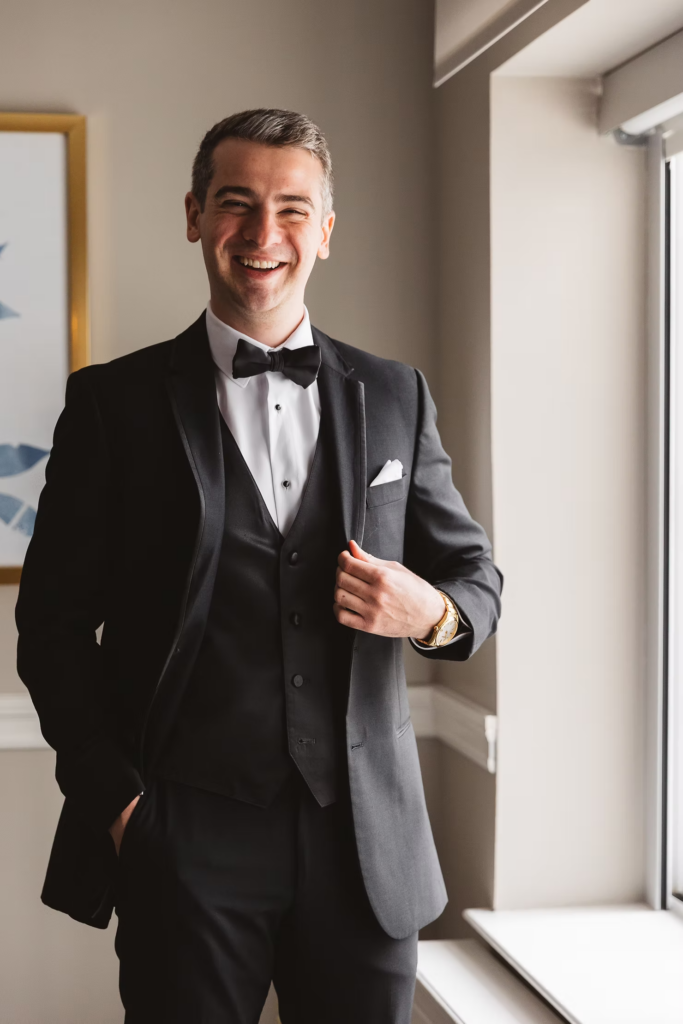 Groom smiles in suit and tie redy for his wedding day. Photographed at The Madison Hotel in Morristown, NJ by wedding photographer Madison Neumann Photography.