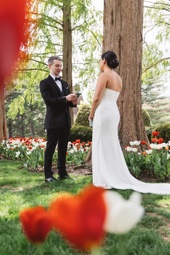 Red and white tulips surround bride and groom as they read each other their vows in private moment on wedding day. Photographed at The Madison Hotel in Morristown, NJ by wedding photographer Madison Neumann Photography.