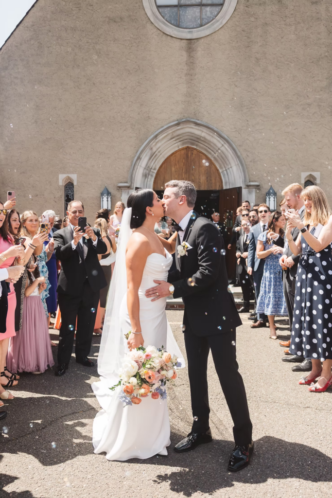 Bride and groom exit their church ceremony as guests cheer and blow bubbles. Photographed at The Madison Hotel in Morristown, NJ by wedding photographer Madison Neumann Photography.