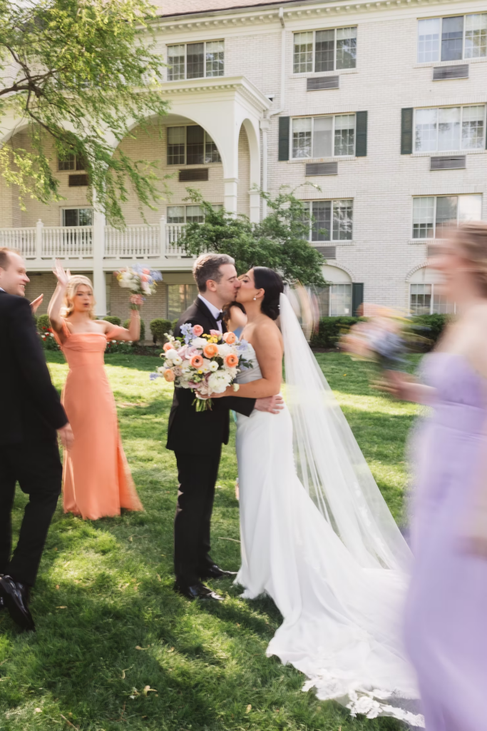 Bridesmaids and groomsmen cheer for bride and groom on their wedding day outside of venue. Photographed at The Madison Hotel in Morristown, NJ by wedding photographer Madison Neumann Photography.