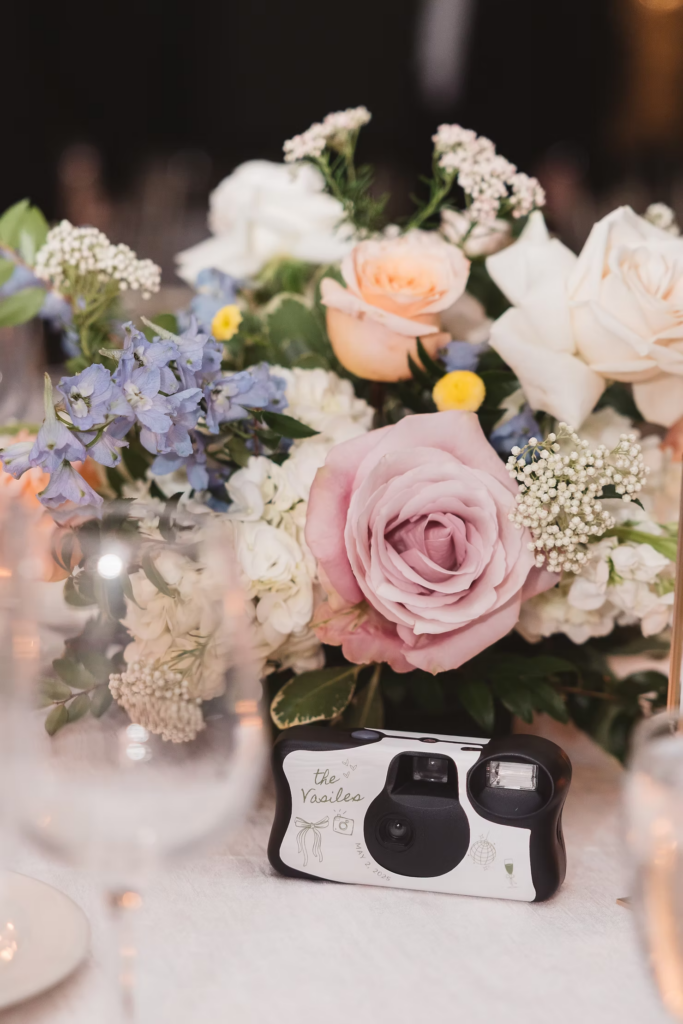 Details of wedding reception table including floral arrangement and customized disposable camera. Photographed at The Madison Hotel in Morristown, NJ by wedding photographer Madison Neumann Photography.