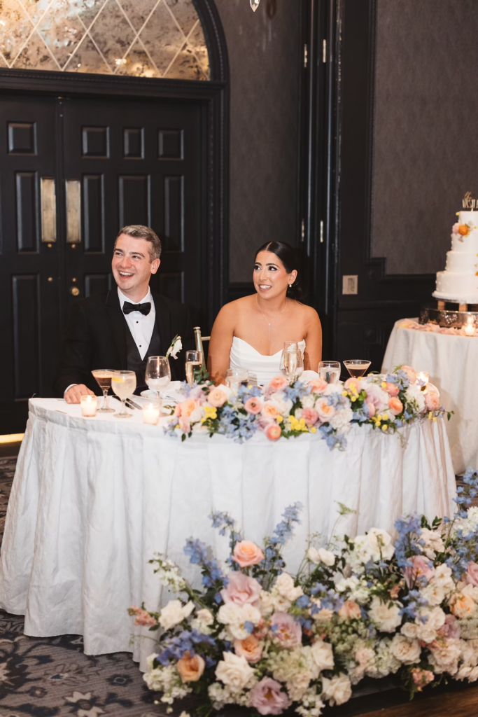 Bride and groom together at sweetheart table with colorful floral arrangement. Photographed at The Madison Hotel in Morristown, NJ by wedding photographer Madison Neumann Photography.