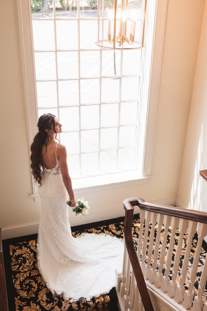 Bride in gown and bouquet by window for portrait after getting ready for wedding at The William Penn Inn in Gwynedd, PA. Photographed by Pennsylvania NJ wedding photographer Madison Neumann Photography.