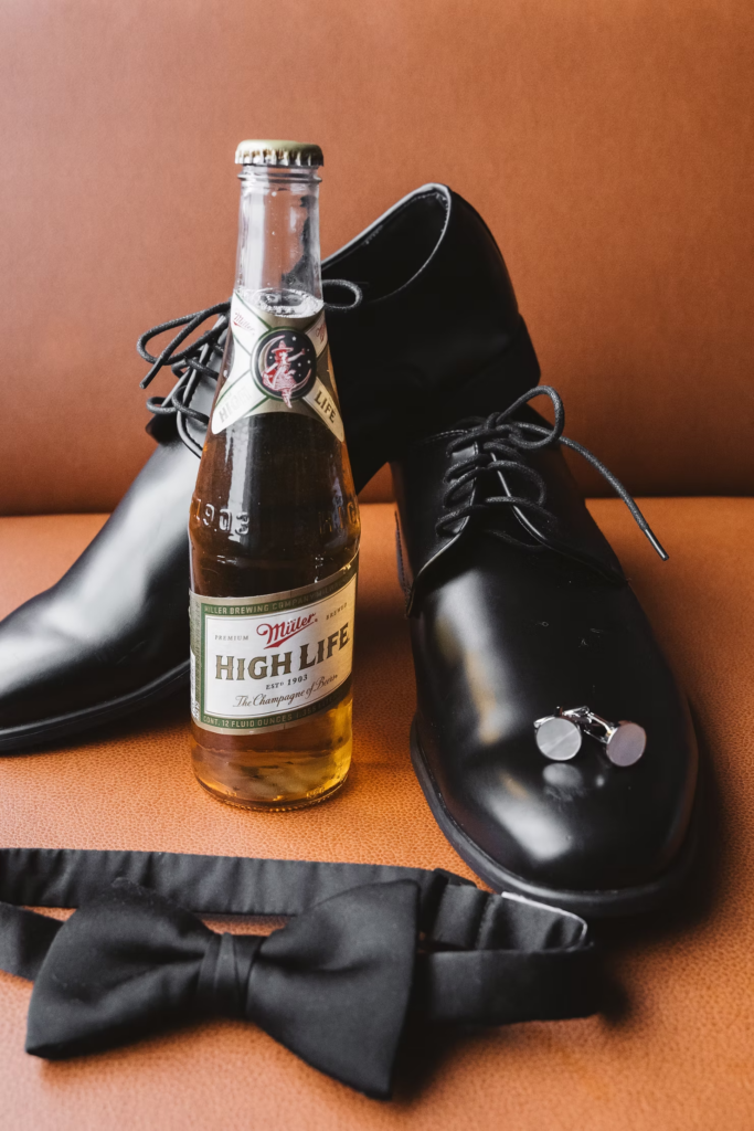 Groom wedding day details and accessories with black tie, dress shoes, cuff links, and Miller High Life beer. Wedding day at Terrain Gardens at DelVal in Doylestown, PA, Photographed by South Jersey, Philly based wedding photographer Madison Neumann Photography.
