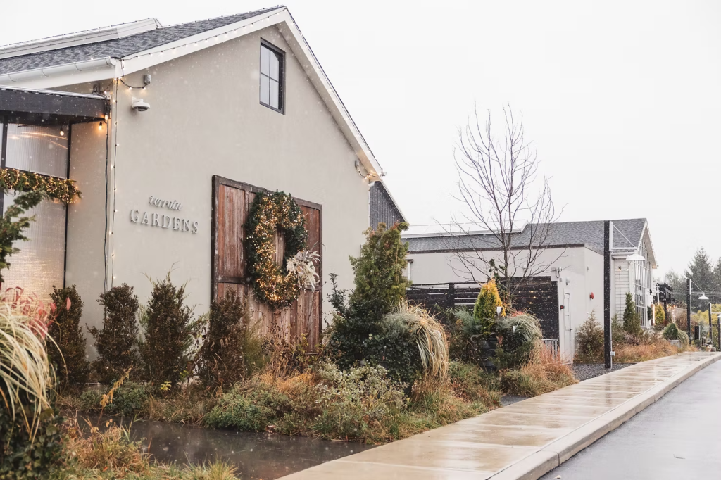 Snow fall outside of venue Terrain Gardens at DelVal in Doylestown, Pennsylvania, with greenery and large wreath. Wedding day photographed by South Jersey, Philadelphia based wedding photographer Madison Neumann Photography.