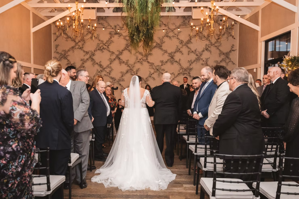 Bride in gown and long veil, walking down the aisle on her wedding day at Terrain Gardens at DelVal in Doylestown, PA. Photographed by South Jersey, Philadelphia based wedding photographer Madison Neumann Photography.