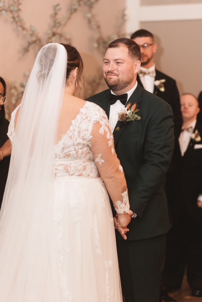 Groom smiles looking at bride at the altar during wedding ceremony at Terrain Gardens at DelVal in Doylestown, Pennsylvania. Photographed by South Jersey, Philadelphia based wedding photographer Madison Neumann Photography.