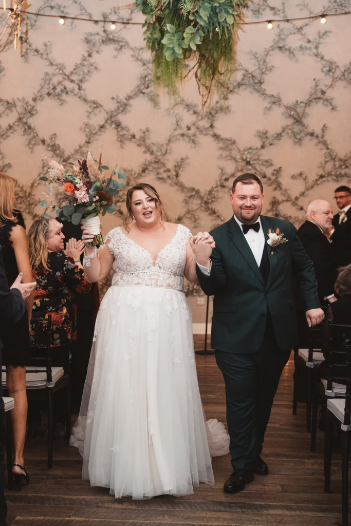 Newlywed bride and groom celebrate after exchanging vows, walking down the aisle hand in hand, just married. Wedding day at Terrain Gardens at DelVal in Doylestown, Pennsylvania. Photographed by South Jersey, Philadelphia based wedding photographer Madison Neumann Photography.