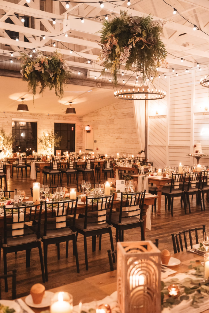 Detail photo of wedding venue reception space at Terrain Gardens at DelVal in Doylestown, Pennsylvania. Tables decorated with candles, greenery, and warm lighting. Photographed by South Jersey, Philadelphia based wedding photographer Madison Neumann Photography.