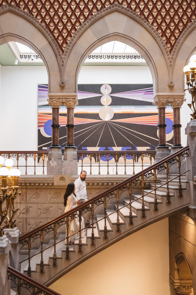 A future bride and groom walk together up the stairs of the Pennsylvania Academy of The Fine Arts for their art museum engagement session in Philadelphia. Photographed by Philly wedding photographer Madison Neumann Photography.