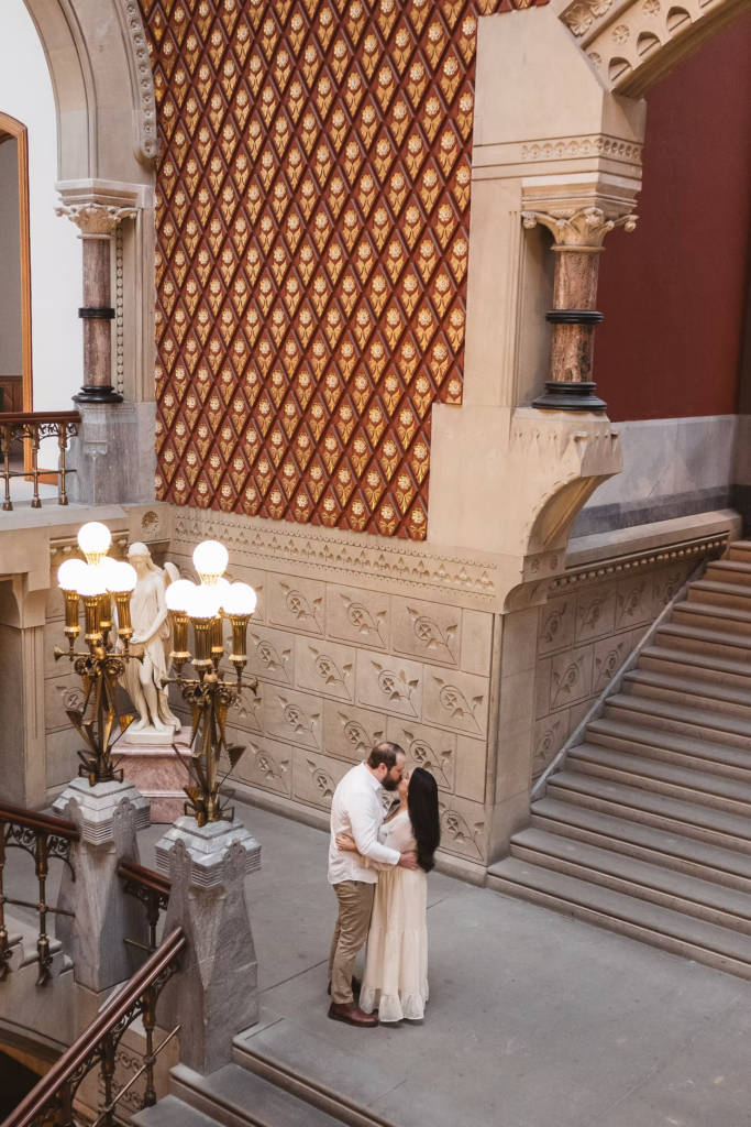 A future bride and groom pose together in the halls of the Pennsylvania Academy of The Fine Arts for their art museum engagement session in Philadelphia. Taken by Philly wedding photographer Madison Neumann Photography.