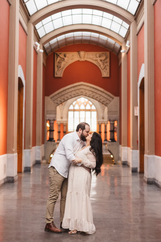 A future bride and groom pose together in the halls of the Pennsylvania Academy of The Fine Arts for their art museum engagement session in Philadelphia. Taken by Philly wedding photographer Madison Neumann Photography.