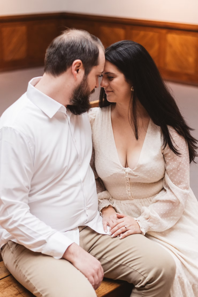 A future bride and groom sit and pose together in the halls of the Pennsylvania Academy of The Fine Arts for their art museum engagement session in Philadelphia. Taken by Philly wedding photographer Madison Neumann Photography.