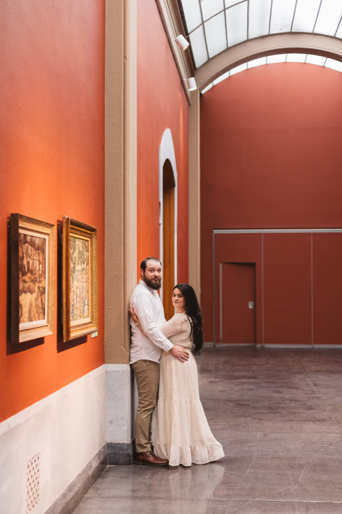 A future bride and groom pose together in front of art pieces at the Pennsylvania Academy of The Fine Arts for their museum engagement session in Philadelphia. Taken by Philly wedding photographer Madison Neumann Photography.