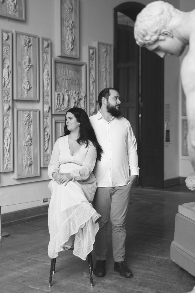 A future bride and groom pose together in the halls of the Pennsylvania Academy of The Fine Arts for their art museum engagement session in Philadelphia, in front of ornate art pieces. Photographed by Philly wedding photographer Madison Neumann Photography.