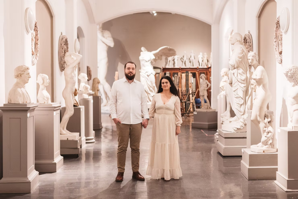 A future bride and groom pose together in a room of sculptures and statues at the Pennsylvania Academy of The Fine Arts for their art museum engagement session in Philadelphia. Photographed by Philly wedding photographer Madison Neumann Photography.