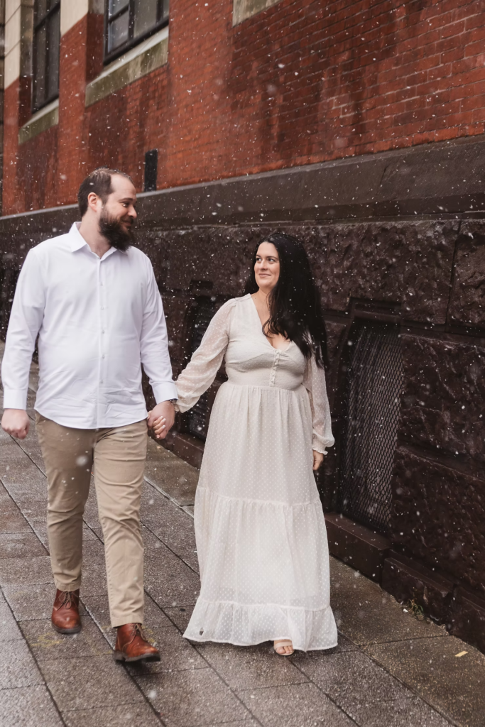 A future bride and groom pose together in the snow in center city Philadelphia. Taken by philly wedding photographer Madison Neumann Photography.