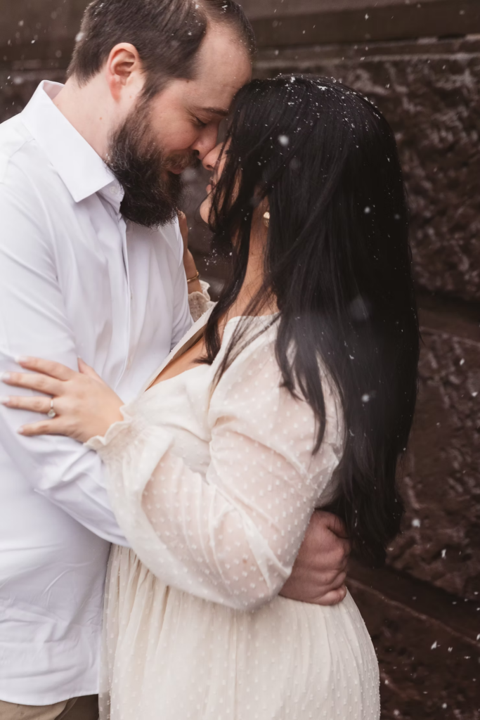 A future bride and groom pose together in the snow in center city Philadelphia. Photographed by Philly wedding photographer Madison Neumann Photography.