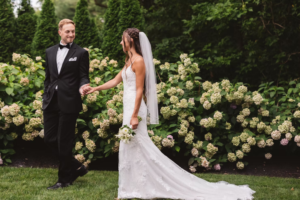 Groom holds brides hand in gown and veil with bouquet for couples portrait for wedding day at The William Penn Inn in Gwynedd, PA. Photographed by PA/NJ area wedding photographer Madison Neumann Photography.