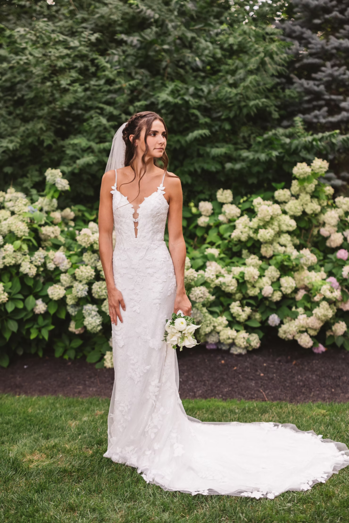 Bride poses in garden by hydrangeas in gown, veil, and bouquet for wedding day at The William Penn Inn in Gwynedd, PA. Photographed by Pennsylvania South Jersey area wedding photographer Madison Neumann Photography.