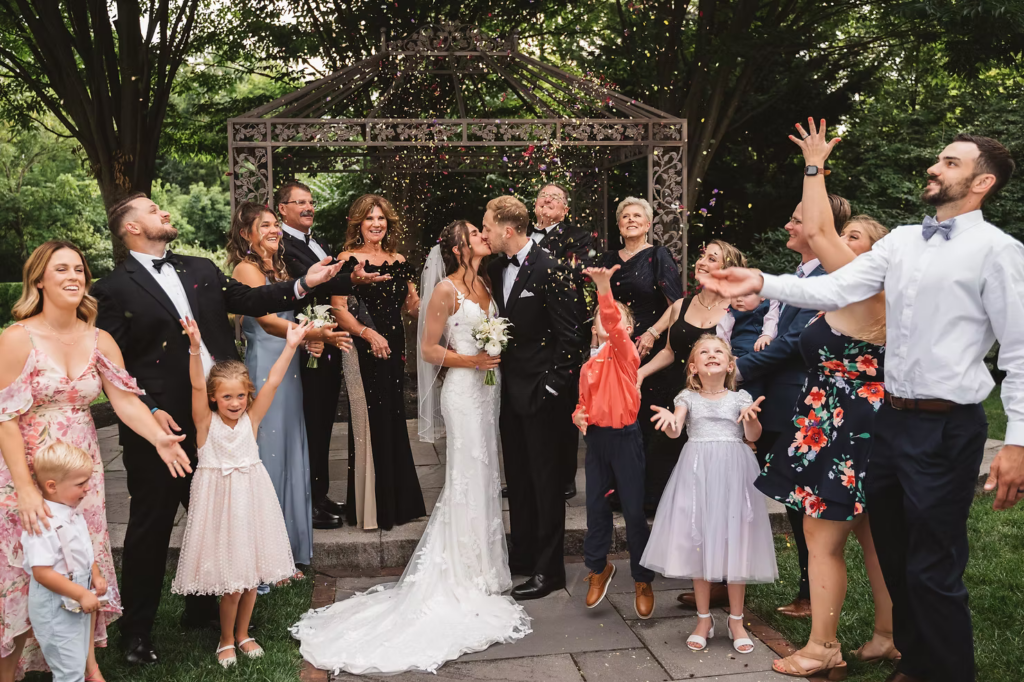 Wedding party celebrates with floral confetti for photo with bride and groom for wedding day at The William Penn Inn in Gwynedd, PA. Photographed by Pennsylvania South Jersey area wedding photographer Madison Neumann Photography.