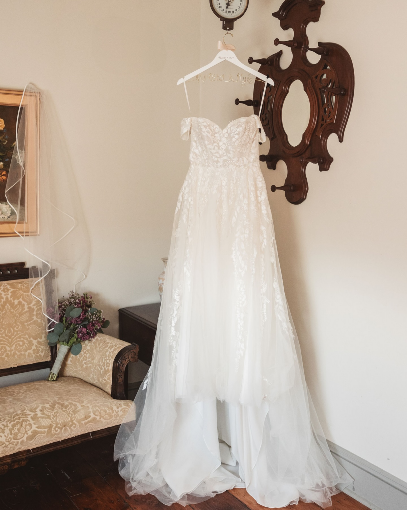 Wedding gown with train and personalized dress hanger reflected in mirror. Wedding day at David's Country Inn in Hackettstown, NJ. Photographed by South Jersey, Philadelphia based wedding photographer Madison Neumann Photography.