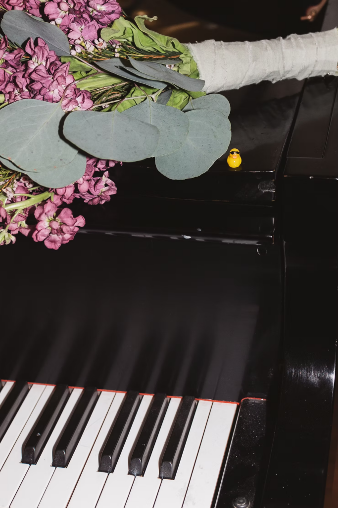 Purple flower bride''s bouquet sits on top of a piano with little rubber duck. Wedding day at David's Country Inn in Hackettstown, NJ. Photographed by South Jersey, Philadelphia based wedding photographer Madison Neumann Photography.