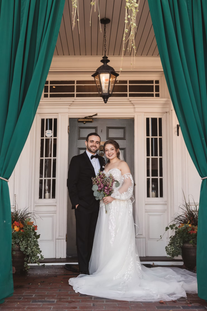 Bride and groom on their wedding day at David's Country Inn in Hackettstown, NJ, standing on porch with green curtains and plants. Photographed by South Jersey, Philadelphia based wedding photographer Madison Neumann Photography.